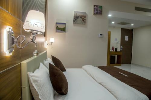 a bedroom with a white bed with a light on it at Vadpadraka Hotel And Resort in Vadodara