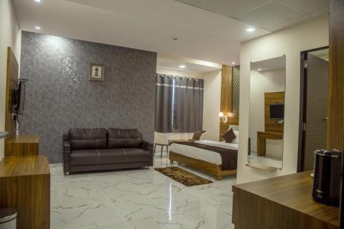 a living room with a couch and a bed in a room at Vadpadraka Hotel And Resort in Vadodara