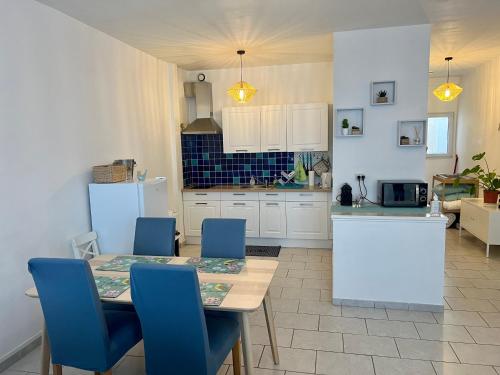 une cuisine avec une table à manger et des chaises bleues dans l'établissement Appartement au calme - Proche centre ville, à Châlons-en-Champagne