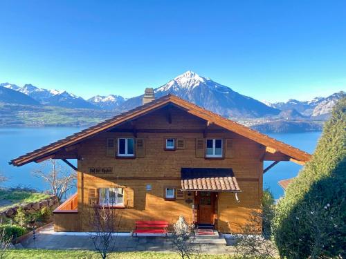 una cabaña de madera en un lago con montañas al fondo en CHALET EGGLEN "Typical Swiss House, Best Views, Private Jacuzzi" en Sigriswil