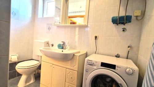 baño pequeño con lavadora y lavamanos en Apartments Ana & Ivan, en Krk