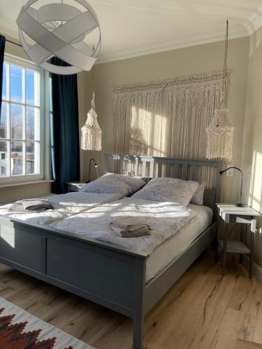 Un dormitorio con una cama grande y una lámpara de araña. en Luxus Lindenhof Apartments -Ferienwohnungen in Friesland an der Nordsee am Naturschutzgebiet Urwald, en Neuenburg