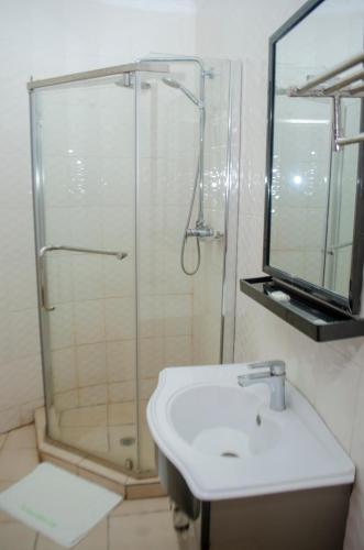 a bathroom with a shower and a sink and a mirror at ROYAL SHALOM HOTEL in Lusaka