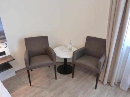 two chairs and a small table in a room at ankerplatz-Hotel garni in Wilhelmshaven