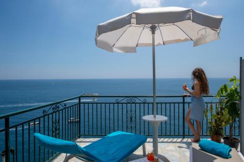 a woman standing on a balcony with an umbrella at Hotel Villa Maria Pia in Praiano