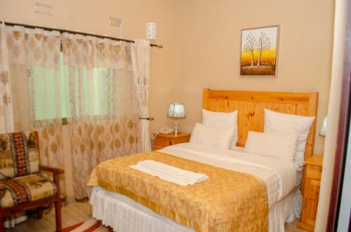 a bedroom with a bed and a chair and a window at ROYAL SHALOM HOTEL in Lusaka