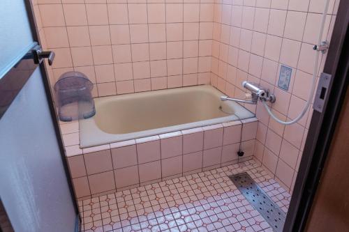 - une salle de bains carrelée de rose pourvue d'une baignoire dans l'établissement MaruHouse, à Nachikatsuura
