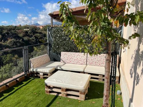 eine Terrasse mit einem Sofa und einem Baum auf dem Balkon in der Unterkunft Mirador del Río in Miraflores de la Sierra