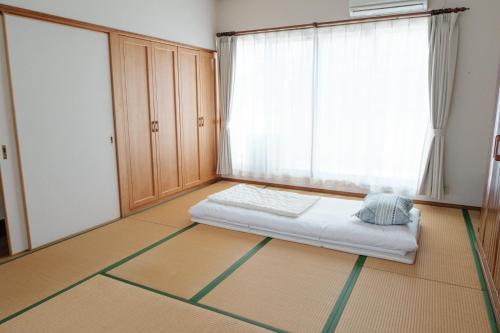 ein Schlafzimmer mit einem Bett und einem großen Fenster in der Unterkunft MaruHouse in Nachikatsuura