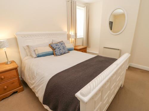 1 dormitorio con cama blanca y espejo en Lower Driftwood, en Amble