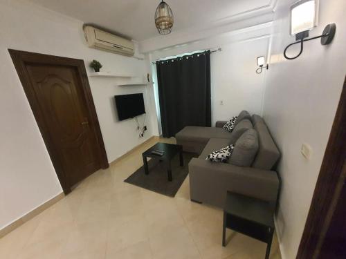 a living room with a couch and a tv at A stylish cozy apartment close to Cairo airport. in Cairo
