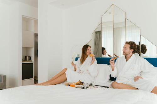 a man and woman sitting on a bed eating food at Hotel Morfeo in Milan