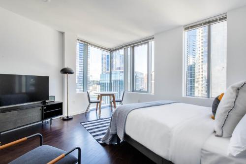 a bedroom with a bed and a tv and windows at Downtown Bellevue Studio w Gym WD nr shops SEA-117 in Bellevue