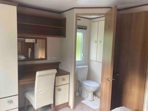 a small bathroom with a toilet and a chair at 2 bedroom chalet in Chwilog on the Llyn Peninsula in Pwllheli