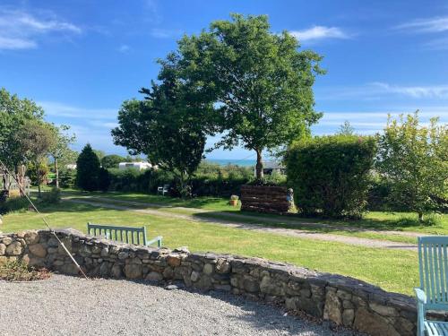 two benches sitting next to a stone wall at 2 bedroom chalet in Chwilog on the Llyn Peninsula in Pwllheli