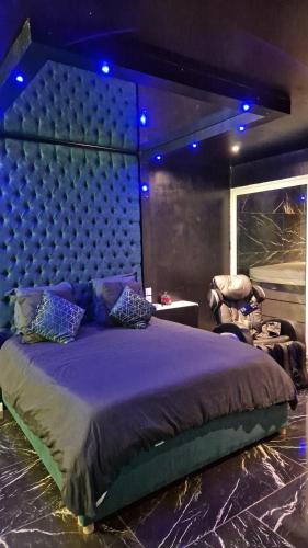 um quarto com uma cama grande com lençóis roxos e luzes azuis em Medusa spa 34* em Montpellier