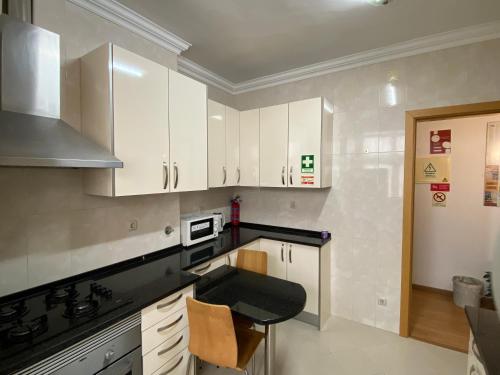 a kitchen with white cabinets and a black counter top at Maiur Apartment in Lisbon