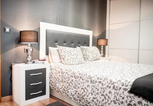 - une chambre avec un lit blanc et une grande tête de lit dans l'établissement Apartamento Cuatro Caminos, à Chantada