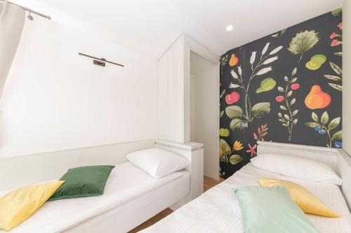 two beds in a room with a wall with fruit mural at Farm Stay Ivankotovi in Prem