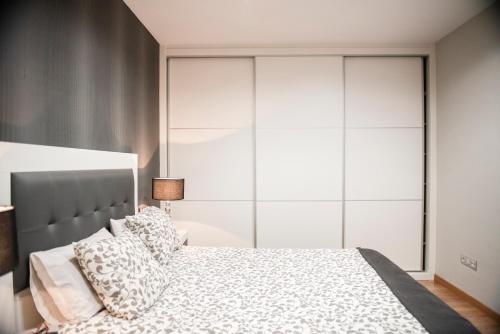 1 dormitorio con 1 cama grande y armarios blancos en Apartamento Cuatro Caminos, en Chantada