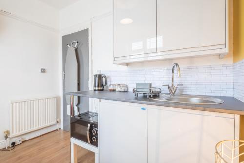 eine Küche mit weißen Schränken und einem Waschbecken in der Unterkunft Cambridge - Private Room 3 by Milton Guest House in Cambridge