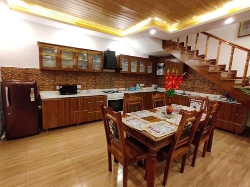 a kitchen with a table with chairs and a staircase at Windflower Villa in Mussoorie