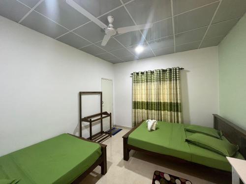 a room with two green beds and a ceiling at The Lake Round Guest House in Kandy