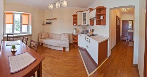 Apartamenty Sun & Snow Krynica Zdrój Pułaskiego في كرينيتسا زدروي: مطبخ وغرفة معيشة مع أريكة وطاولة