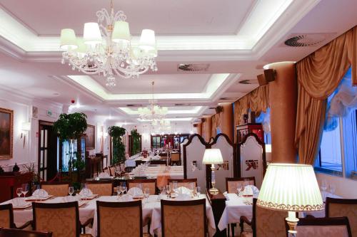 a restaurant with white tables and chairs and a chandelier at Apart-hotel Integra in Banja Luka