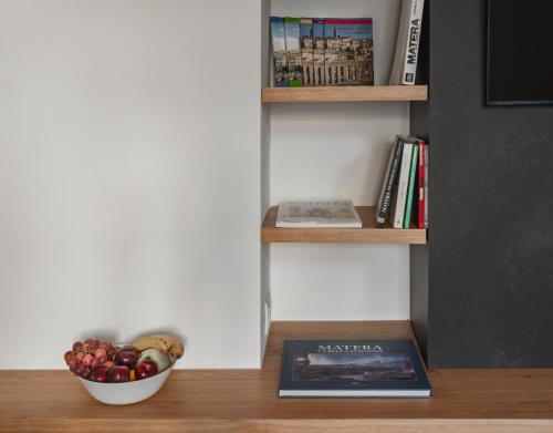 a bowl of fruit and a book on a shelf at DOMUS DE ARMENIS in Matera
