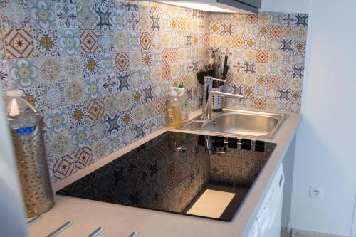 - une cuisine avec un évier et un mur en carrelage dans l'établissement El Sama-In , Piscine chauffée, à LʼIsle-sur-la-Sorgue