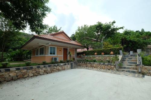 a house with a stone retaining wall and a driveway at The Triple M Mountain Resort in Ban Muang Ton Mamuang