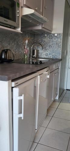 une cuisine avec des armoires blanches et un évier dans l'établissement Les Jardins 2 Port de Plaisance et piscine 2, au Grau-du-Roi