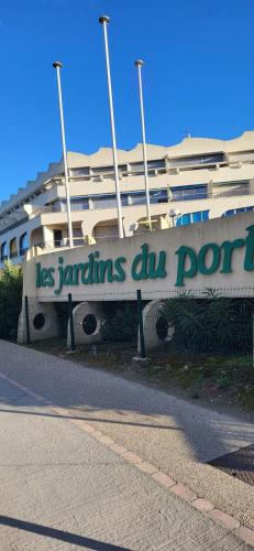 un bâtiment avec un panneau indiquant les ports de las zantens dun dans l'établissement Les Jardins 2 Port de Plaisance et piscine 2, au Grau-du-Roi