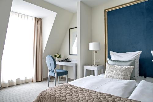 a bedroom with a bed and a desk with a chair at Dorint Parkhotel Meißen in Meißen