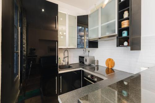 une cuisine avec des armoires noires et blanches et un évier dans l'établissement Nice 34m well located - Montmartre district, à Paris