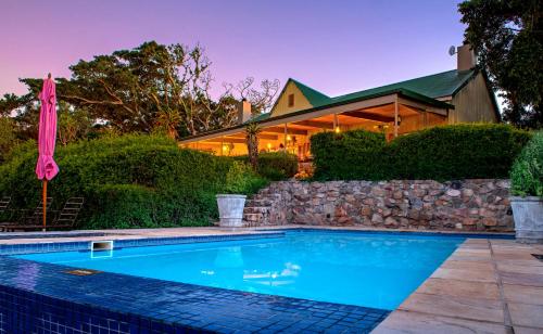 a swimming pool in front of a house at Camp Figtree by The Oyster Collection in Addo