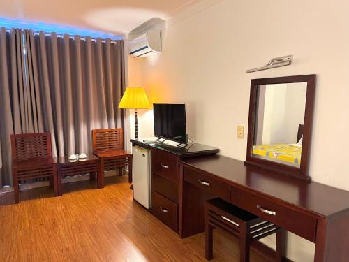 Zimmer mit einer Kommode mit einem Spiegel und einem Schlafzimmer in der Unterkunft Phung Long Hotel in Ho-Chi-Minh-Stadt