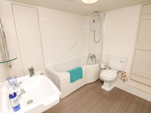 a white bathroom with a tub and a toilet at The Bathing House in Ashsprington