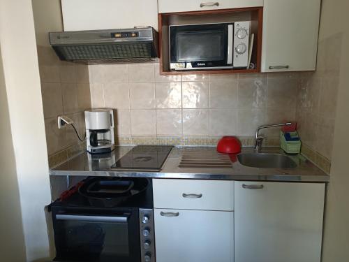 a small kitchen with a stove and a microwave at EL MANZEl 102 in Houmt Souk