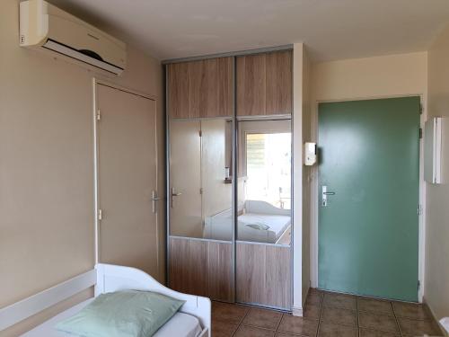 a bedroom with a bed and a glass cabinet at Grand studio lumineux à Saint-Gilles-les-Bains in Saint-Gilles les Bains