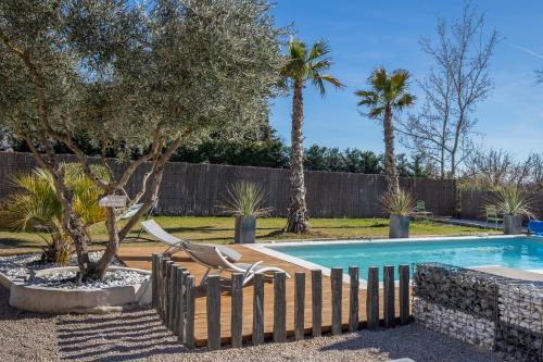 a swimming pool with chairs and trees in a yard at In Elsama piscine chauffée in LʼIsle-sur-la-Sorgue