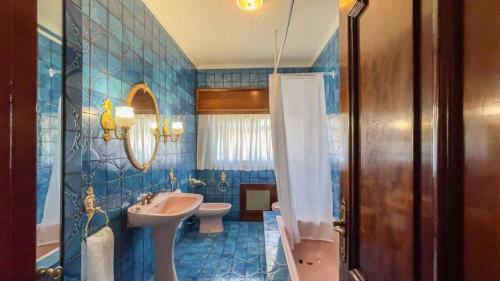 een blauw betegelde badkamer met een wastafel en een toilet bij Playa Miño Sombreu in Miño