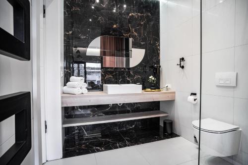 a bathroom with a sink and a black marble wall at Cristal Baltic in Ustka