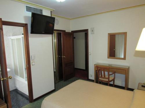a hotel room with a bed and a desk and a television at Hotel Virgen del Camino Pontevedra in Pontevedra