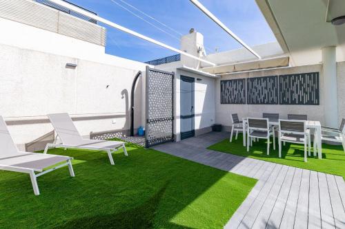eine Terrasse mit Stühlen, einem Tisch und Gras in der Unterkunft ApartUP Patacona Sunrise Duplex in Valencia
