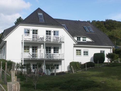 a large white house with a balcony at Traumblick und Komfort - lichtdurchflutete 85 qm Wohnung nahe Südstrand Göhren inklusive Schwimmbad und Sauna im AHOI Sellin in Göhren