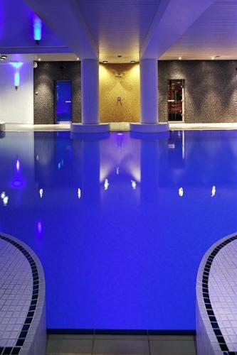 a swimming pool with blue lighting in a building at Novotel Cardiff Centre in Cardiff