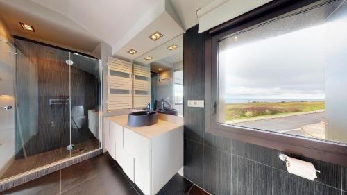 Barrika的住宿－SEE AND SEA，一间带水槽和玻璃窗的浴室