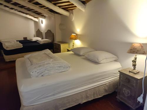 una camera con 2 letti con lenzuola e cuscini bianchi di grand gîte de charme en Cévennes a Fressac